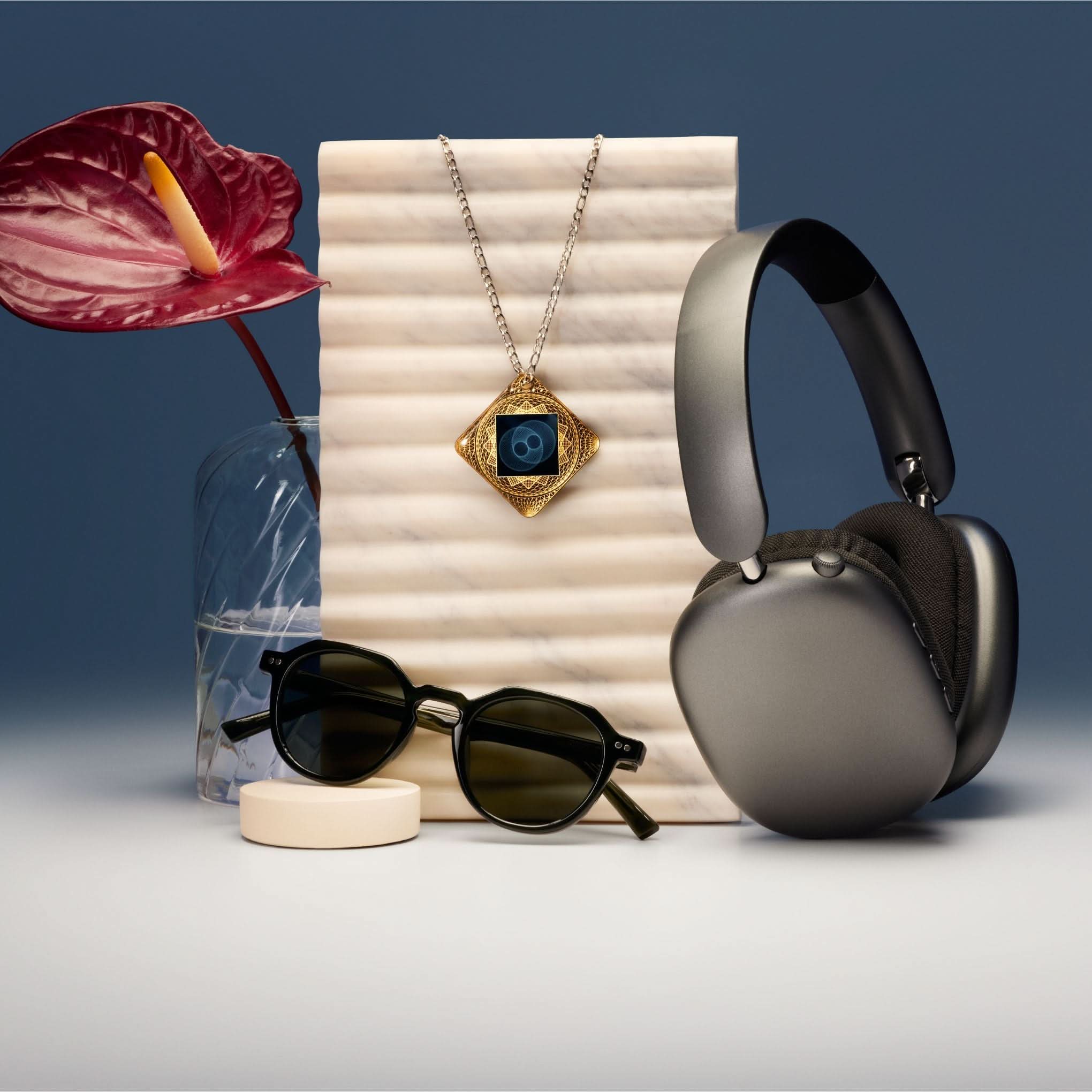 Lifetune Flex EMF protection pendant styled with sunglasses and headphones in lifestyle flat lay