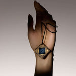 Person holding Lifetune Flex EMF protection pendant with black cord necklace