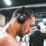 Athlete wearing headphones with Lifetune One EMF sticker during intense gym workout
