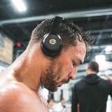 Athlete wearing headphones with Lifetune One EMF sticker during intense gym workout