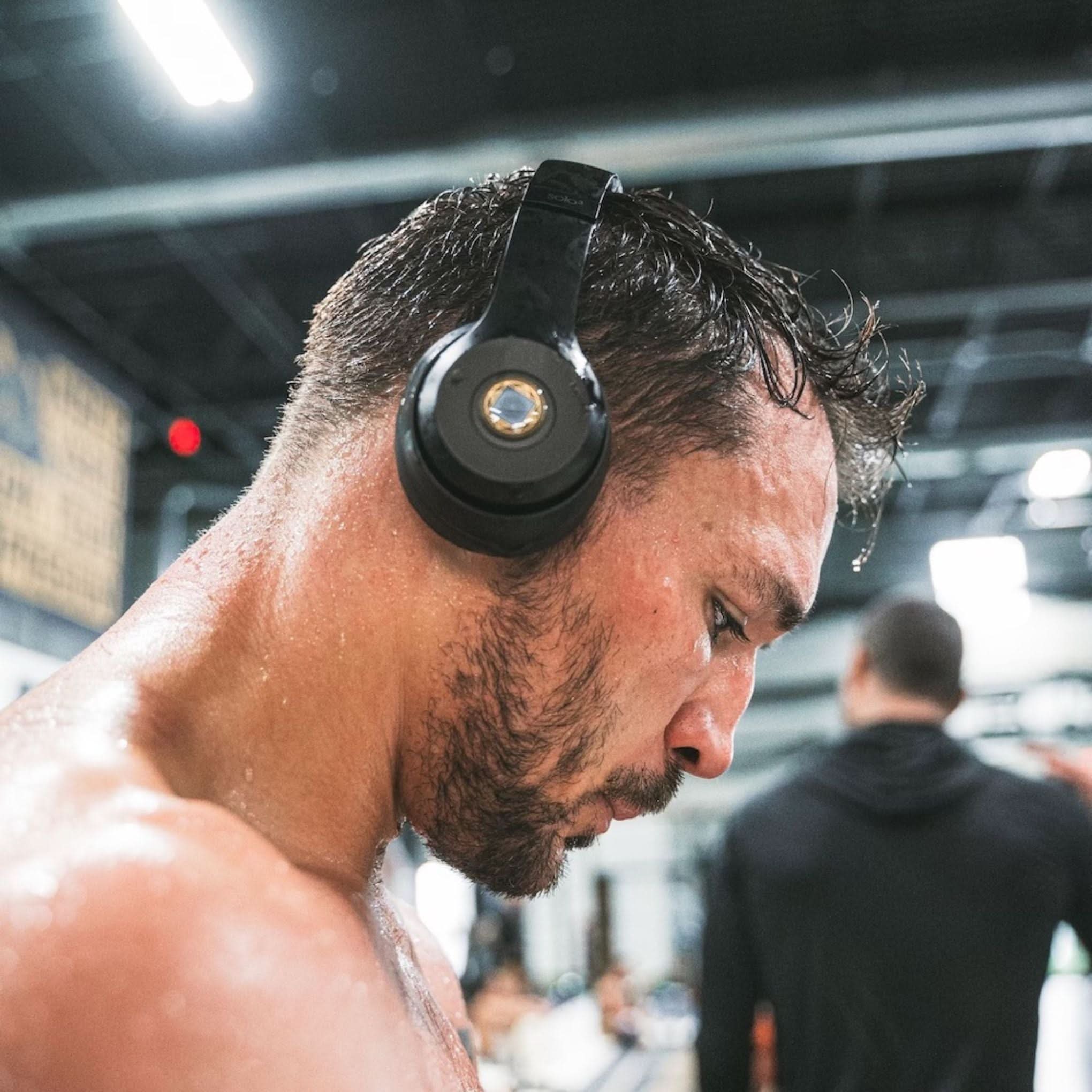 Athlete wearing headphones with Lifetune One EMF sticker during intense gym workout
