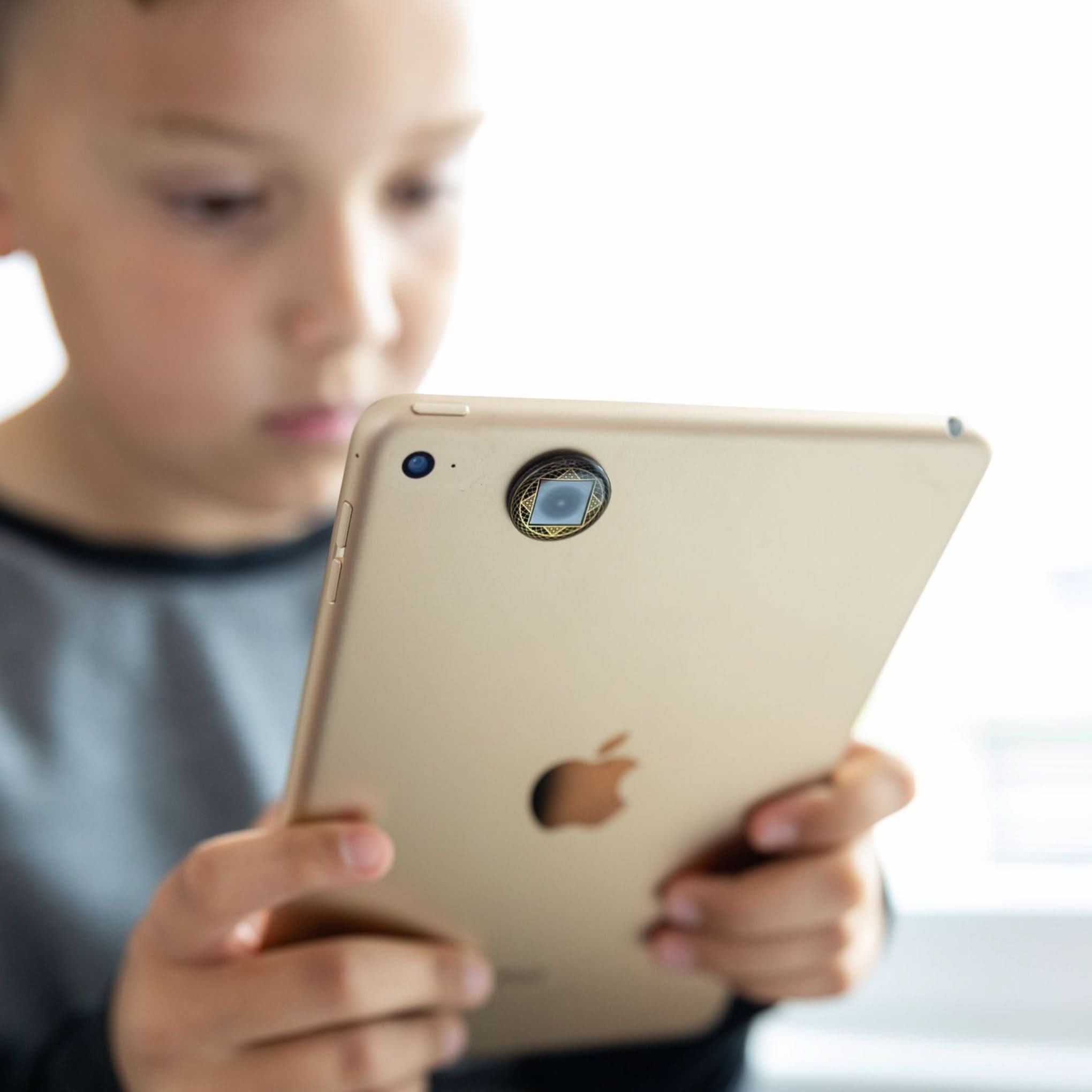Child using tablet with Lifetune One EMF protection sticker applied to reduce exposure to screen radiation