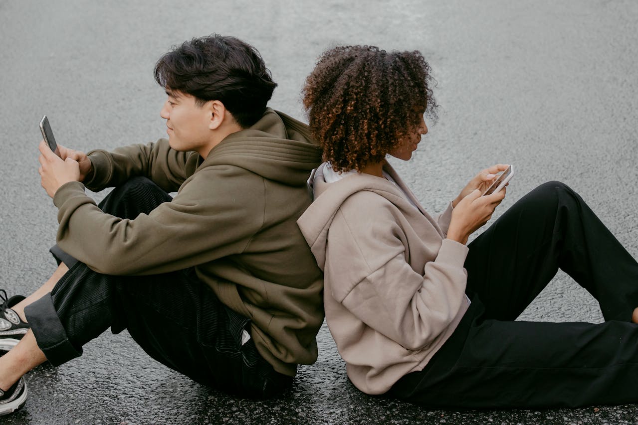People sitting on the ground looking at their iPhones