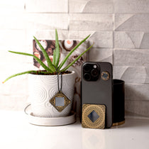 Phone case with decorative elements next to a potted plant on a surface.